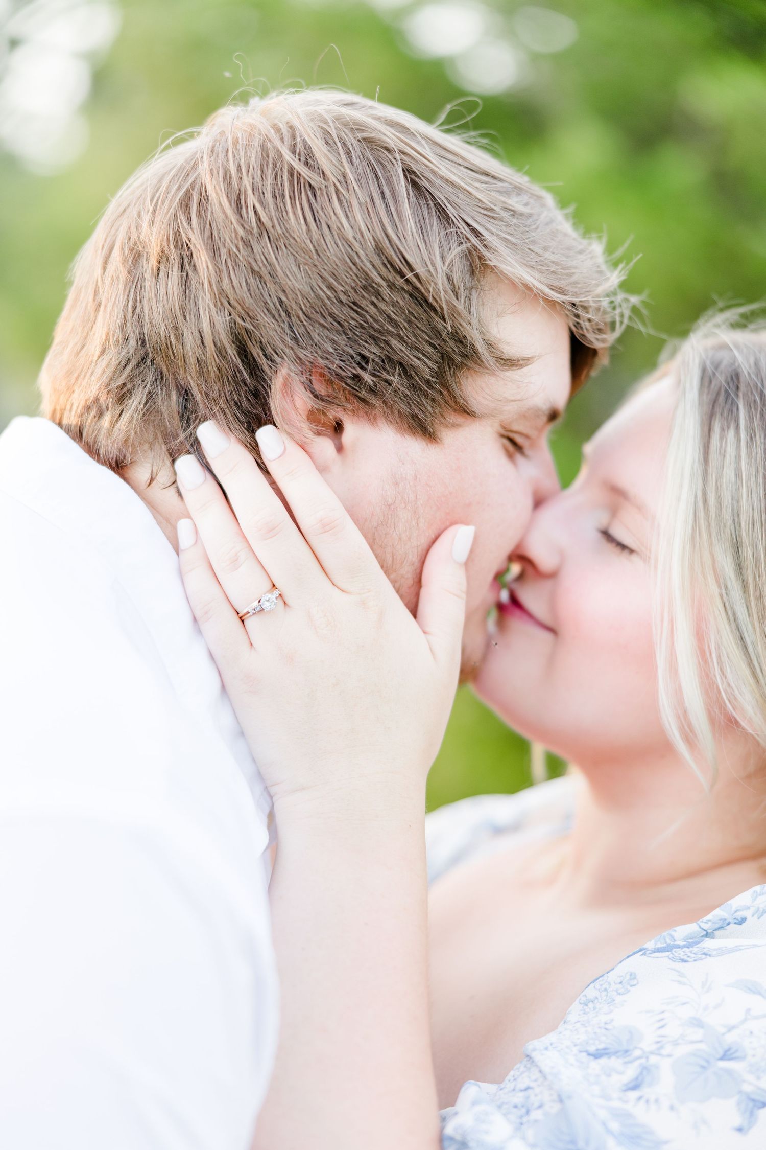 A close-up romantic moment showing an engagement ring glinting in natural light.