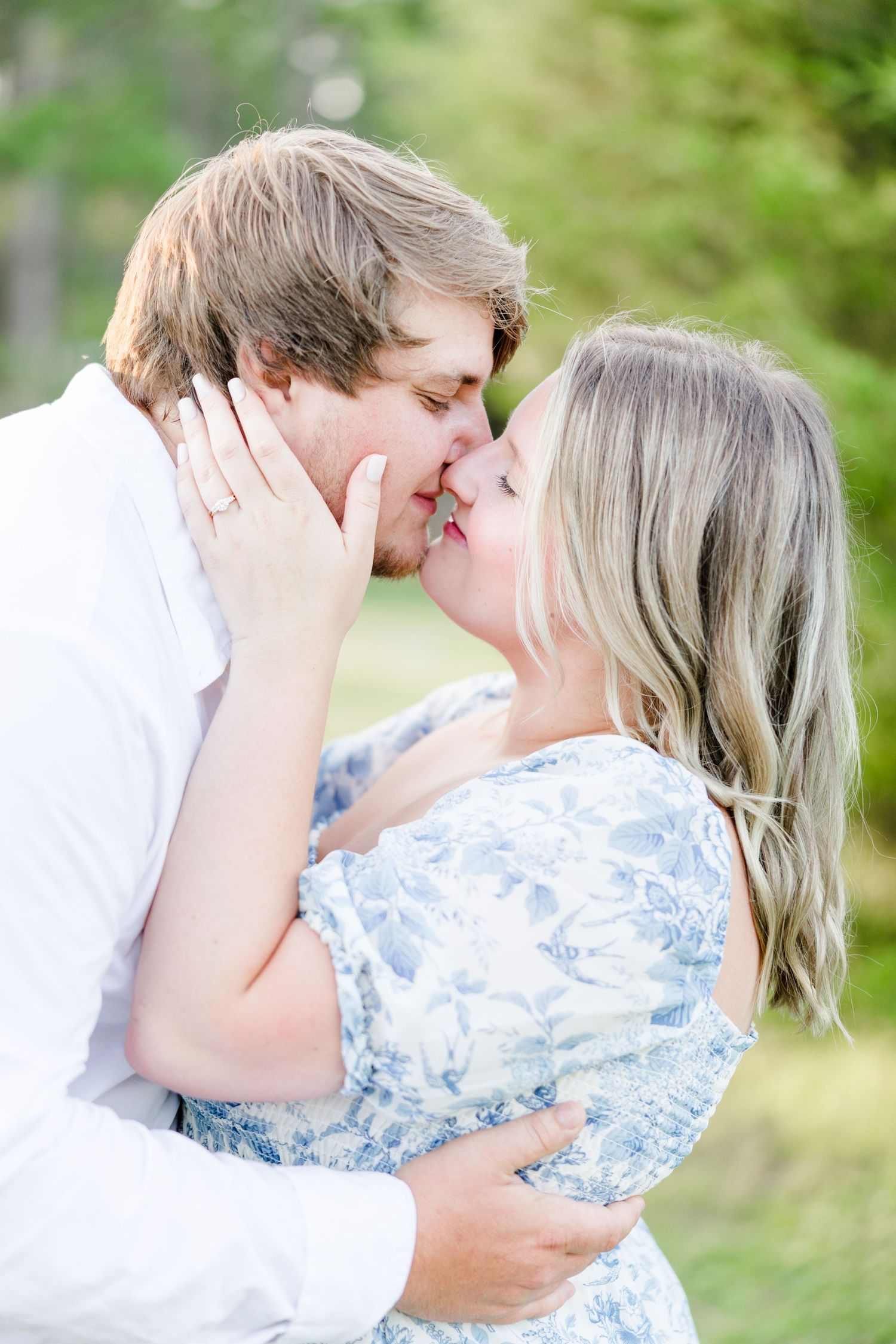 An intimate embrace captured in soft natural lighting with a forest backdrop.