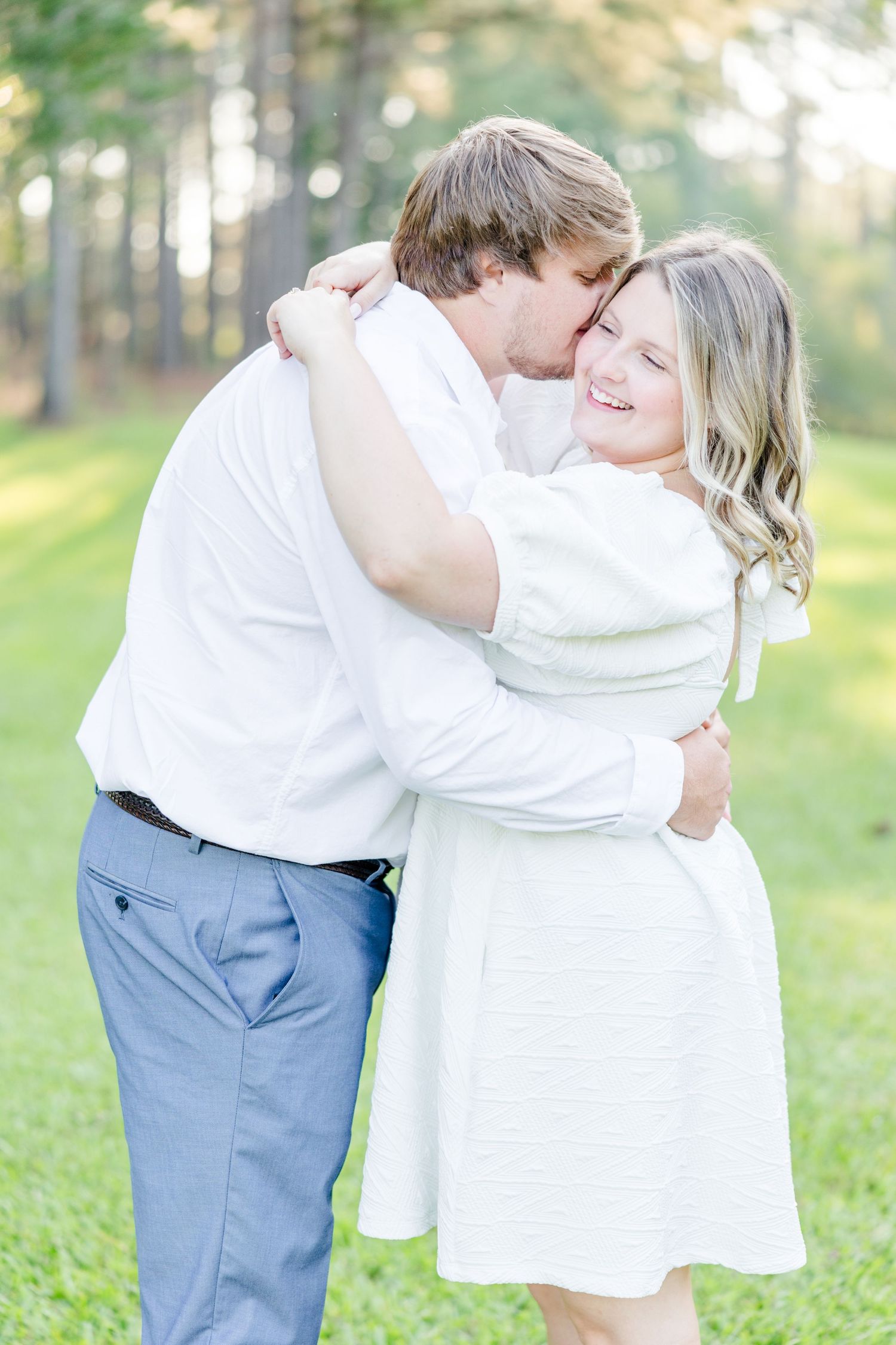 Romantic couple in white clothing share tender moments during their outdoor photo session.