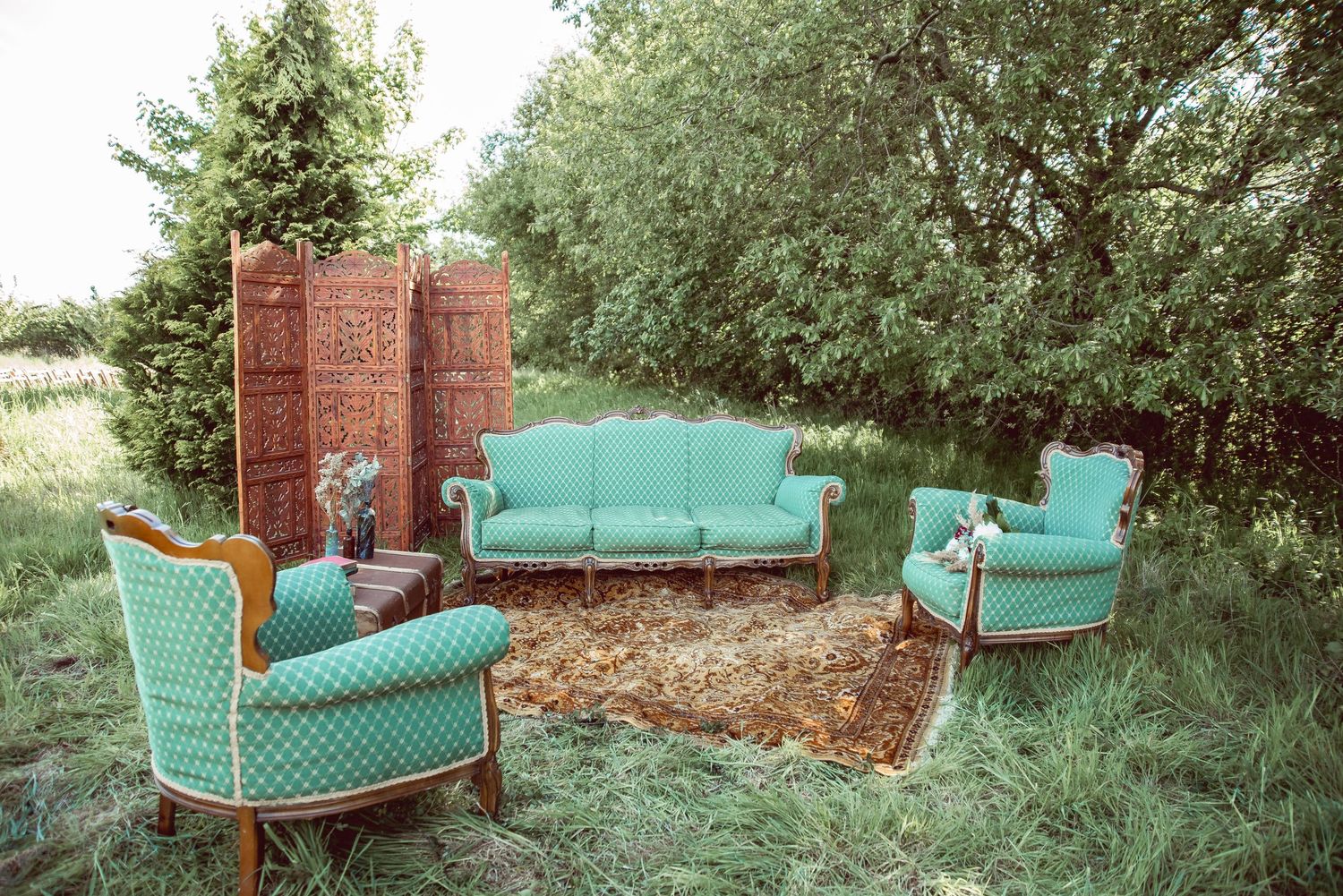 Vintage teal chaise lounges arranged in a garden setting with brick wall backdrop.