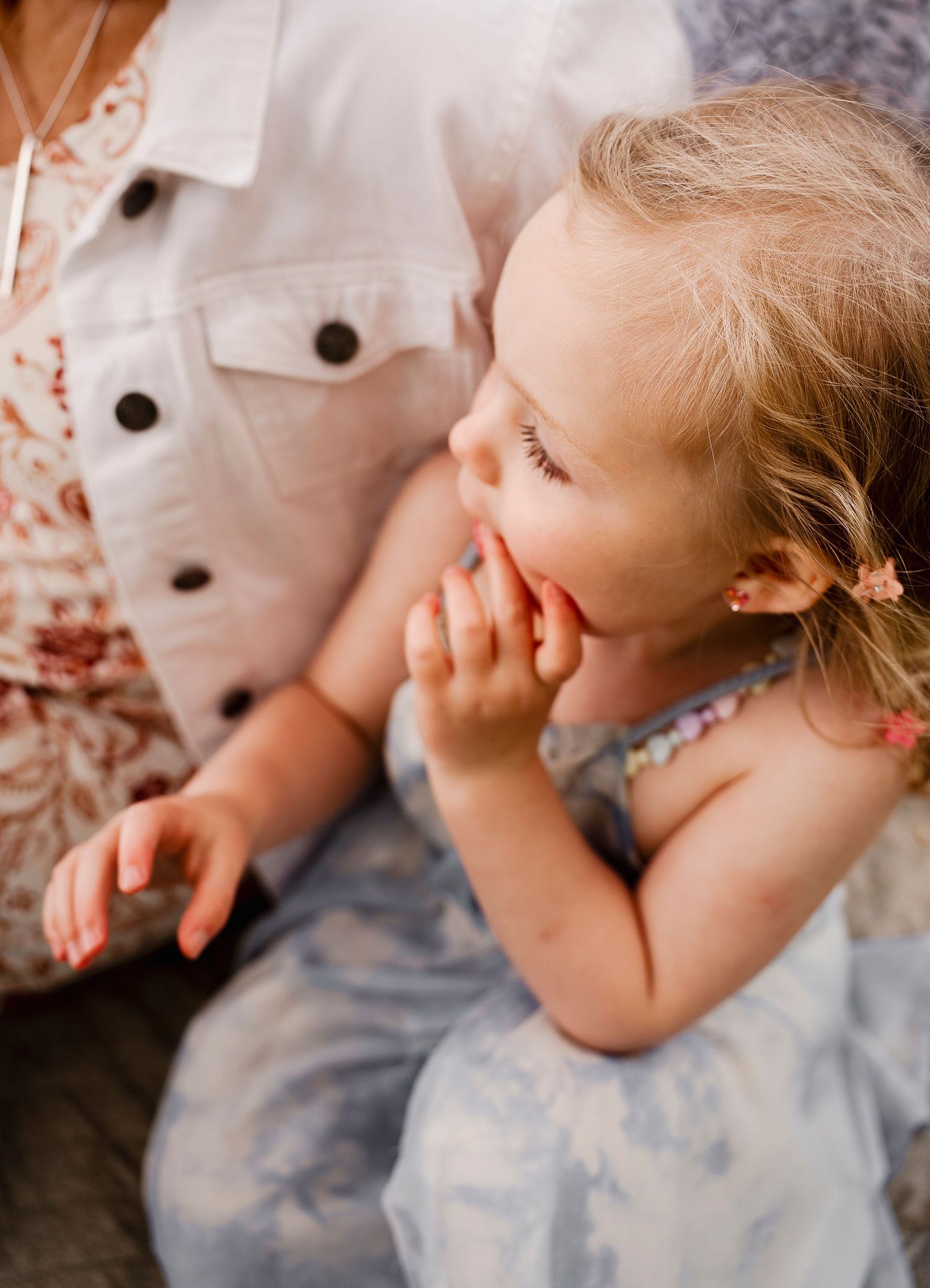 A candid moment of laughter and joy captured in soft warm tones with floral and white clothing details.