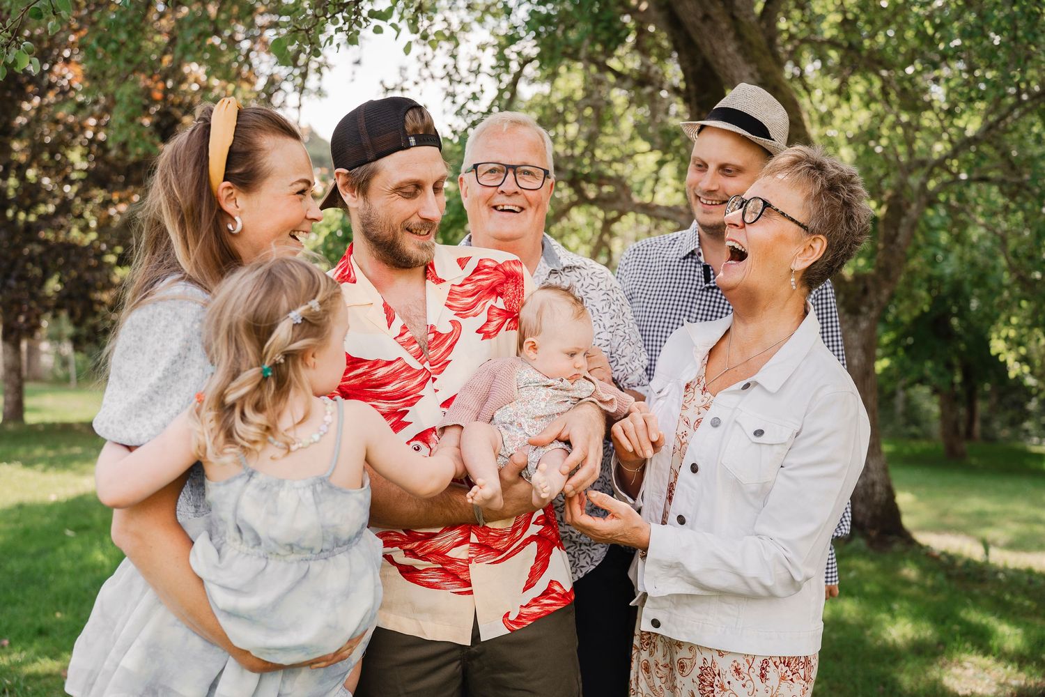 A group shares joyful laughter during an outdoor summer photoshoot.