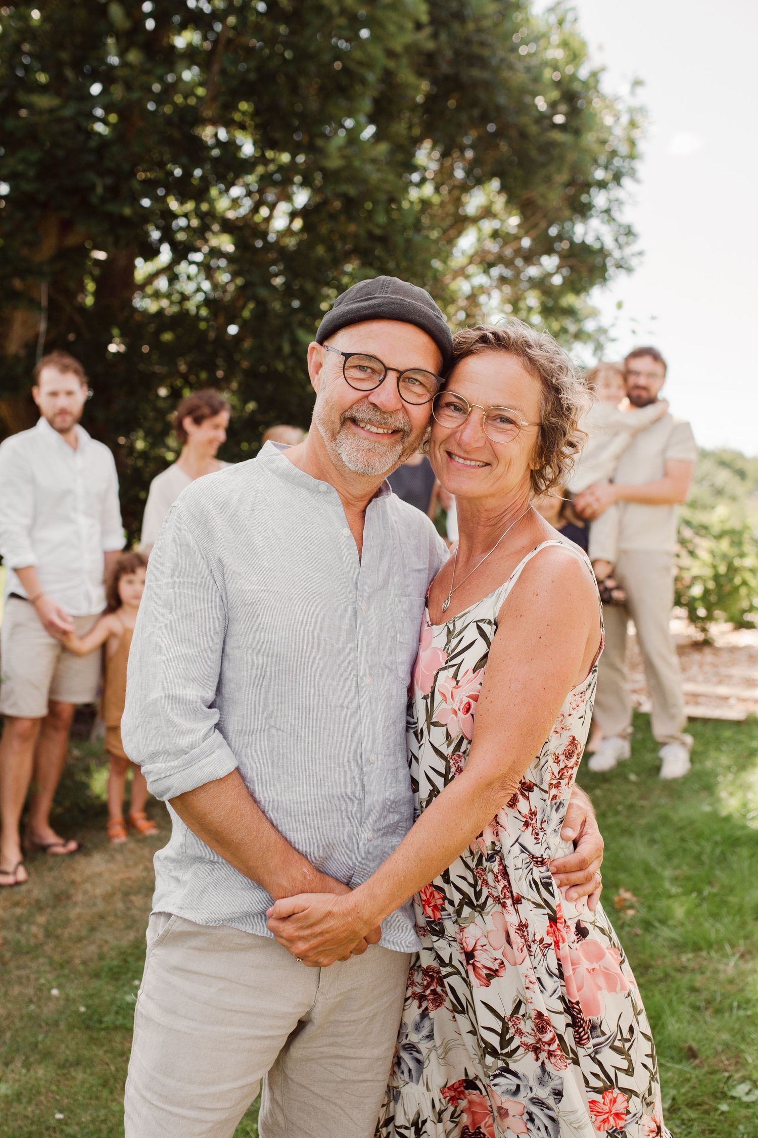 A couple embraces and smiles warmly at an outdoor summer gathering.