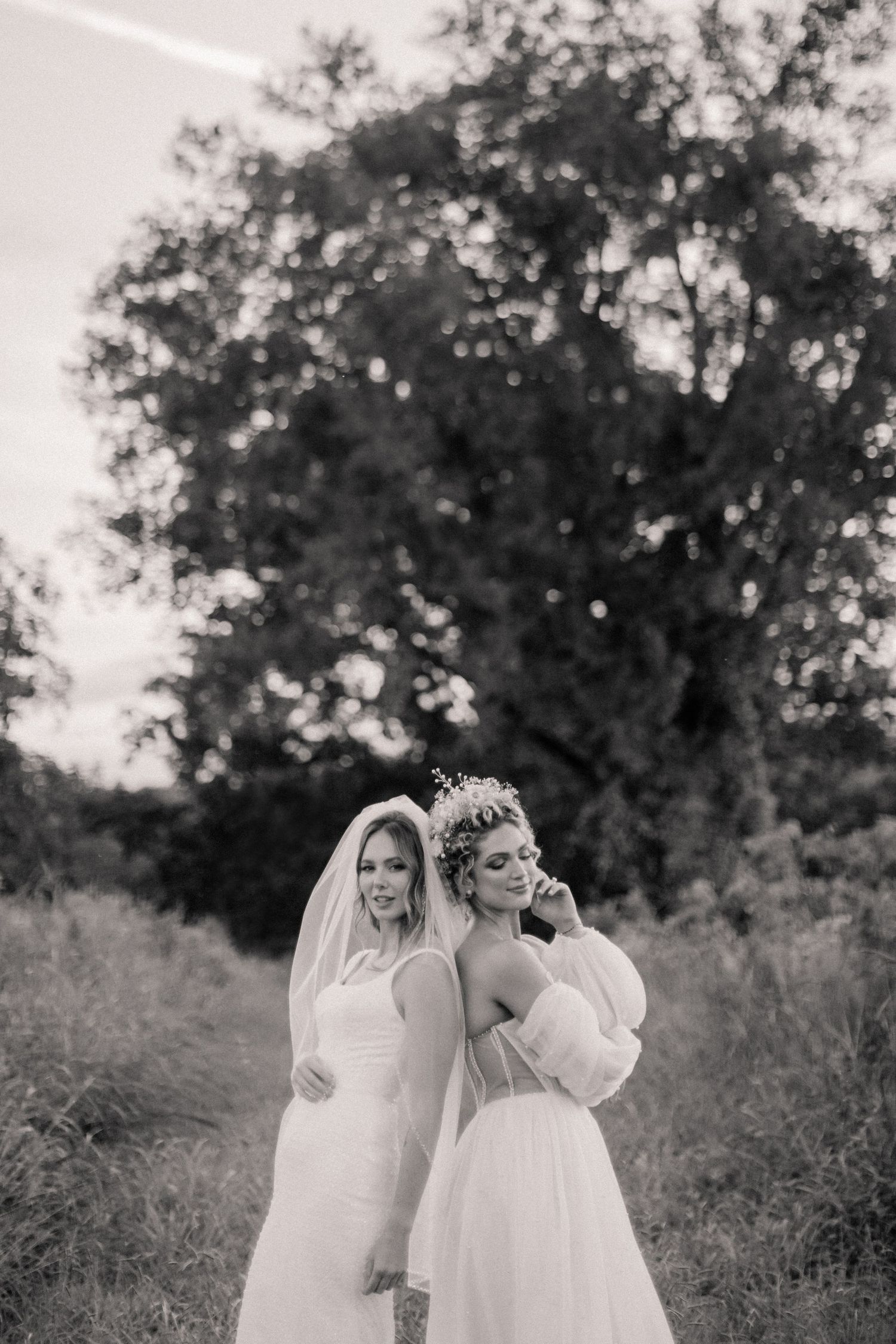 Black and white portrait of two wedding dresses styled against a natural outdoor backdrop.