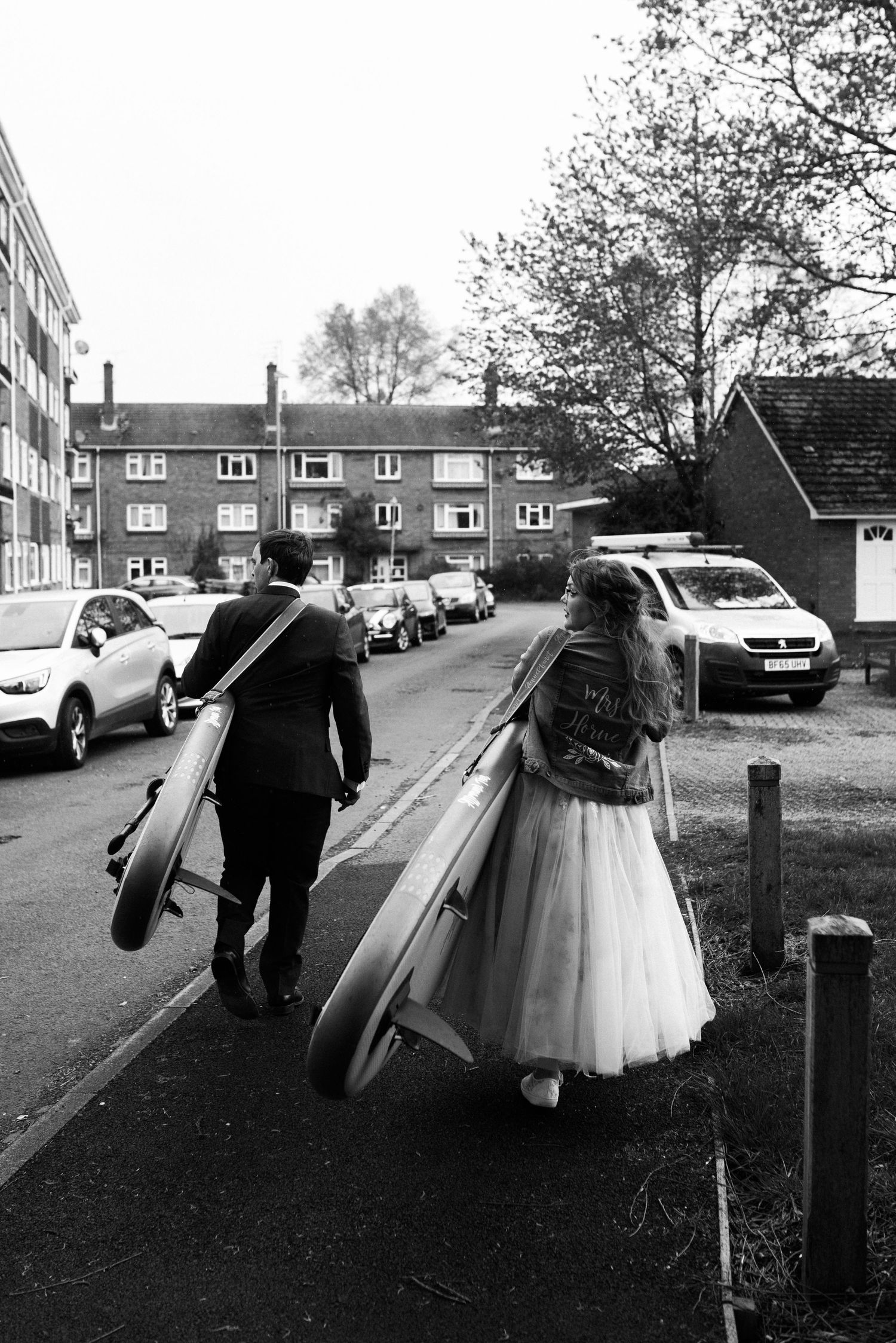 A couple carries musical instruments down a residential street after their wedding ceremony.