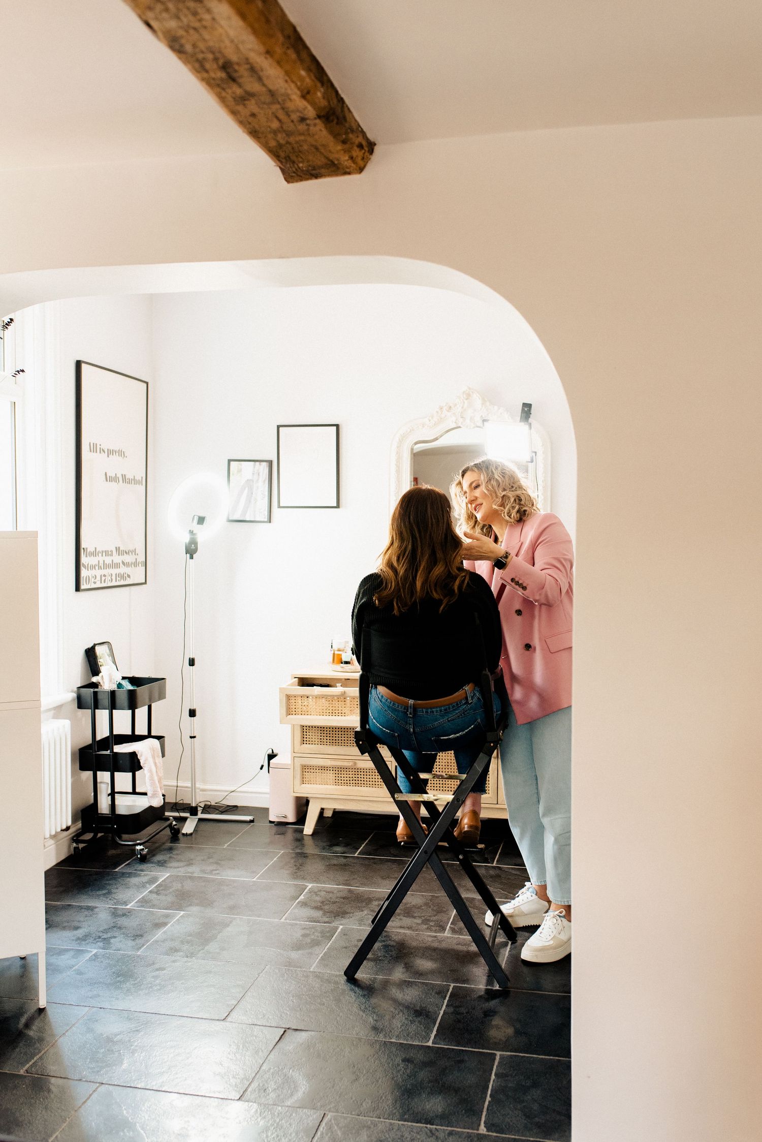 Professional beauty studio with black tile floor and arched doorway showing styling station.