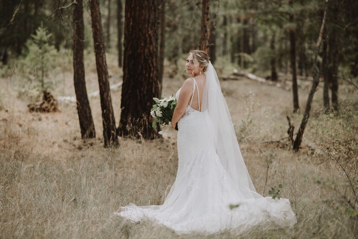 Bridal portrait of bride holding her bouquet. She is wearing her wedding dress and veil.