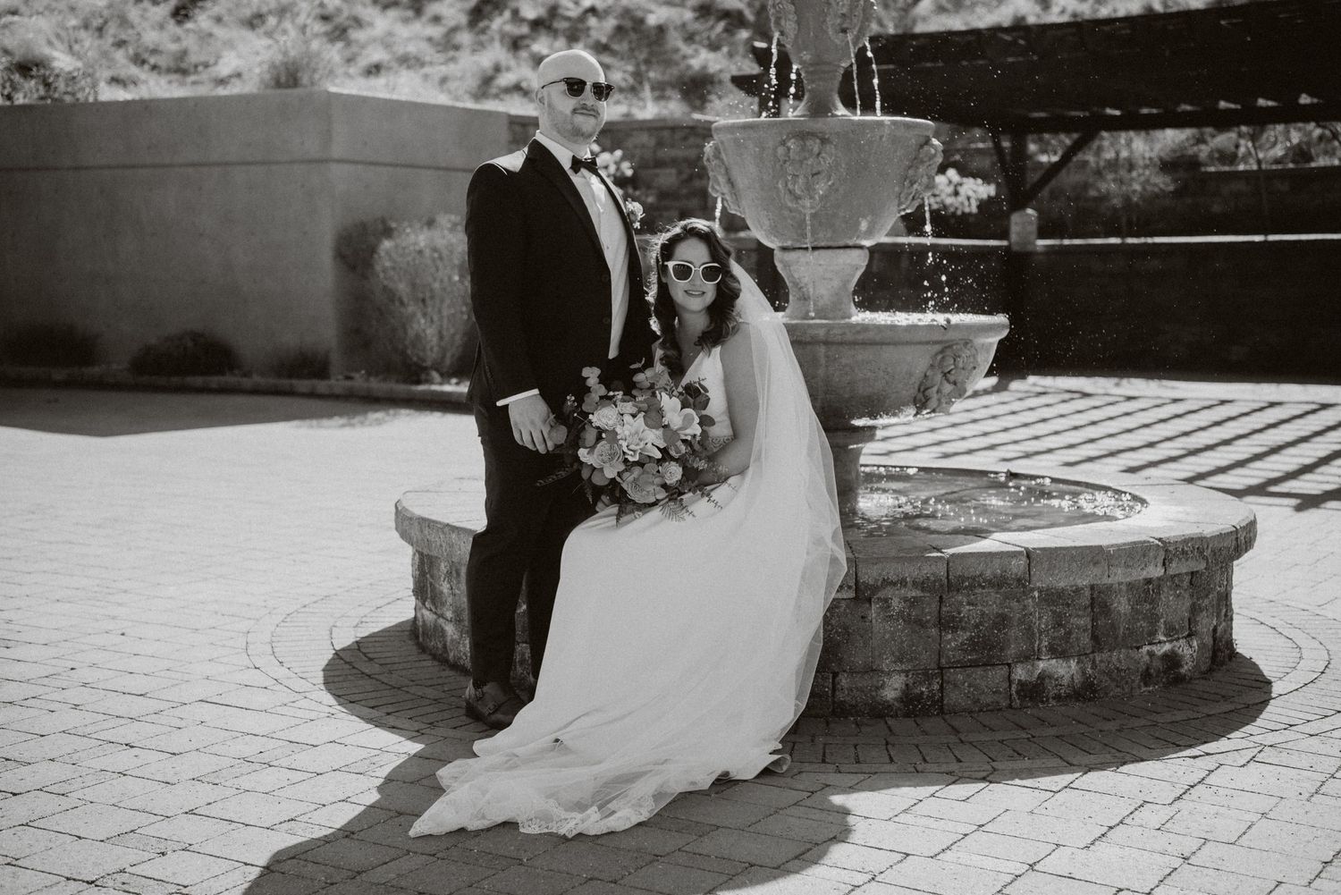 Wedding couple posing by stone fountain in black and white photography.