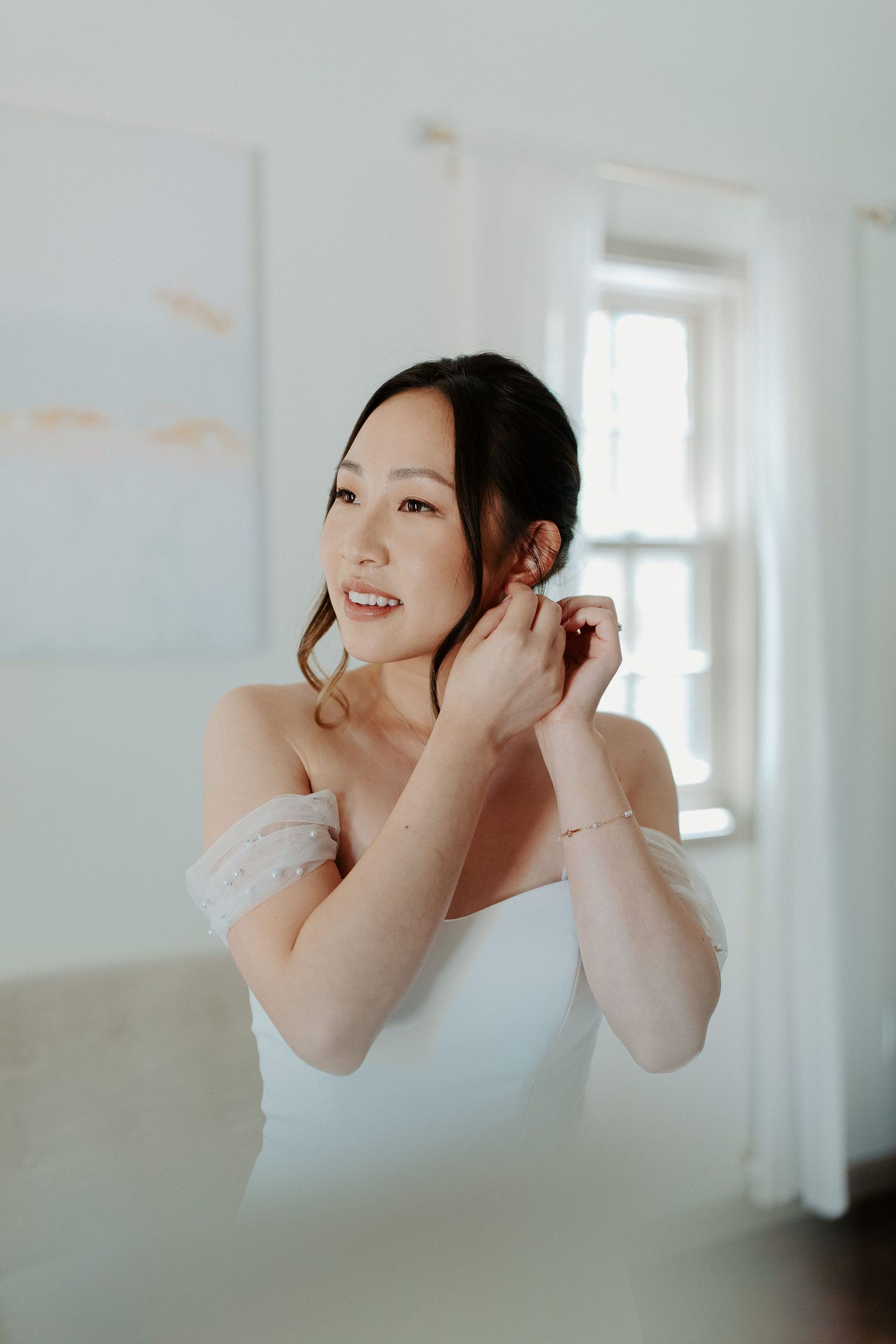 White wedding dress preparation with a soft natural light streaming through the window.